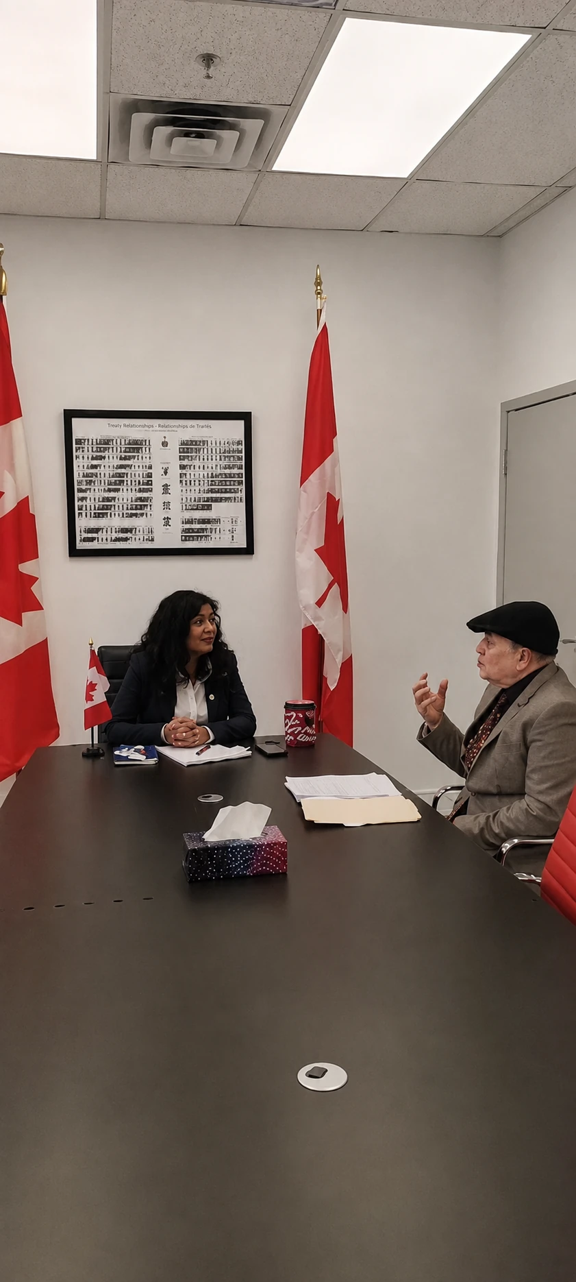 Asjad Hussain taking part in a discussion with Canadian flags in the room